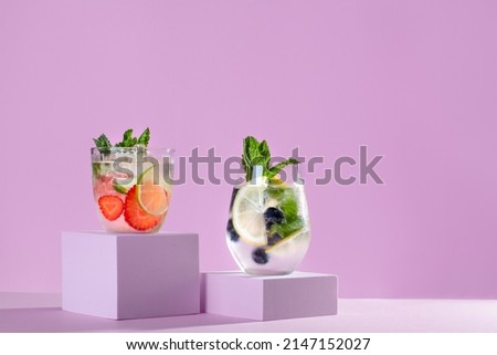 Summer refreshing fruit and berry infused detox water on podiums in pink color, creative summer beverages background