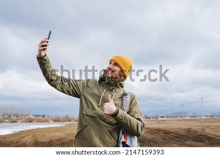Selfie against the sky. A guy smiling and taking pictures of himself on his phone, a traveler with a backpack in a northern country, a smile on his face, a hipster happy. High quality photo