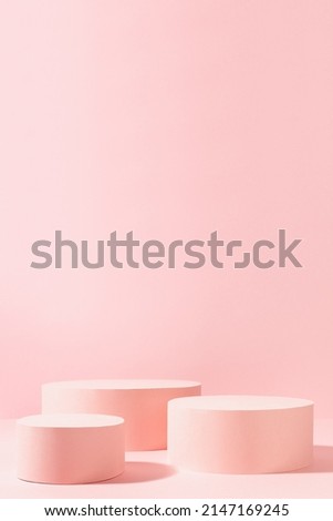 Sweet girlish pastel pink stage mockup with group of three circle podiums in sunlight with shadow on soft light for advertising, presentation cosmetic product or goods, design, copy space, vertical. Royalty-Free Stock Photo #2147169245