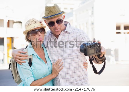 Happy tourist couple taking a selfie in the city on a sunny day