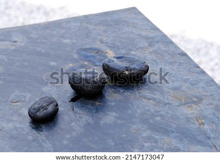 Three volcanic stones placed on a gray granite table in nature for peaceful reflection