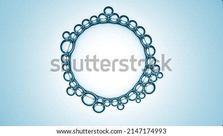 Macro shot of big transparent bubble with small ones connected around it on blue radial ramp background | Abstract skin care cosmetic ingredients concept