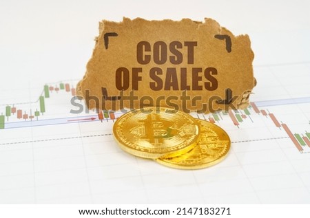 Business and technology concept. On the chart with quotes, there are bitcoins and there is a sign with the inscription - COST OF SALES