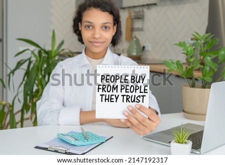 Closeup on wooman holding a card with text PEOPLE BUY FROM PEOPLE THEY TRUST, business concept image with soft focus background and vintage tone.