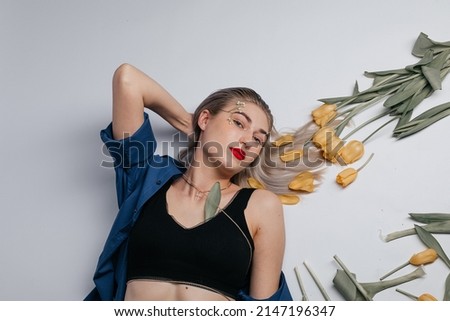 Girl in a blue shirt with yellow flowers in her hands on a white background