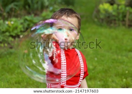 A child plays with soap bubbles in nature in summer.
