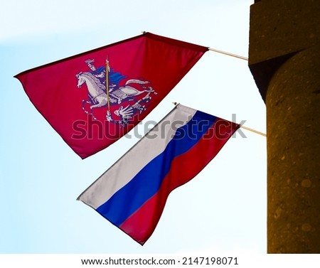 Flags of Russia and Moscow waving in wind are installed on the building. State symbols of Russian Federation and city of Moscow. Street decoration during holidays.