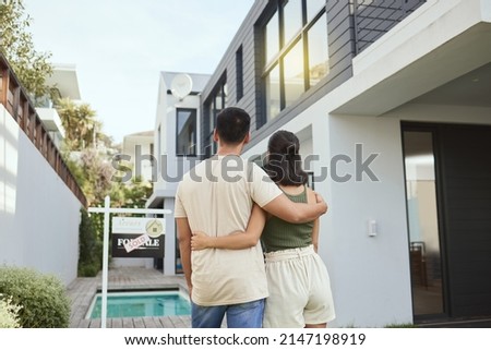 This is ours now. Rearview shot of a young couple standing outside their new home. Royalty-Free Stock Photo #2147198919