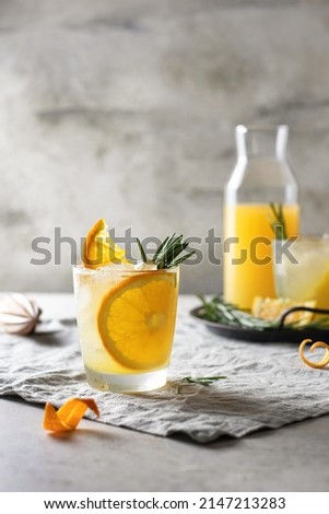 Cold and refreshing orange punch cocktail with orange slice and rosemary on textured background. Summer drink. Vertical orientation, text space Royalty-Free Stock Photo #2147213283
