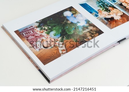 a book with new year photos of big family at home on a white background. Photobook is gift. professional photographer and designer. printing of photos and journals in photo laboratory