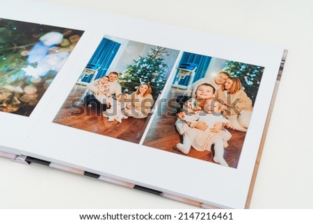 a book with new year photos of big family at home on a white background. Photobook is gift. professional photographer and designer. printing of photos and journals in photo laboratory Royalty-Free Stock Photo #2147216461