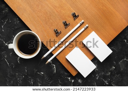 Photo of blank stationery set and coffee cup on wooden board background. Corporate identity template. Flat lay