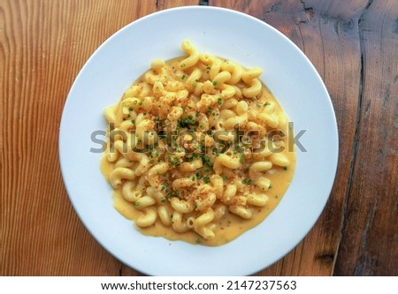 A chef prepared bowl of gourmet cavatappi macaroni and cheese from above on a rustic wood restaurant table Royalty-Free Stock Photo #2147237563