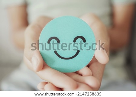 Hands holding green happy smile face paper cut, good feedback rating,think positive, customer review, assessment, child wellness,world mental health day, Compliment Day Royalty-Free Stock Photo #2147258635