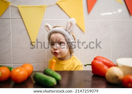 baby in rabbit ears eats vegetables Easter. High quality photo