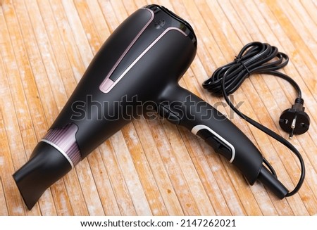 Photo of black blow dryer over wooden surface. Royalty-Free Stock Photo #2147262021