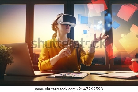Metaverse technology concept. Woman with VR virtual reality goggles is working in the office. Futuristic lifestyle. Royalty-Free Stock Photo #2147262593
