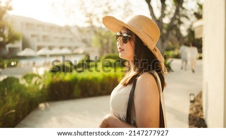 Young Asian woman with hat relaxing beside the pool at luxury hotel. travel and summer concept background.,cover banner concept vocation summer