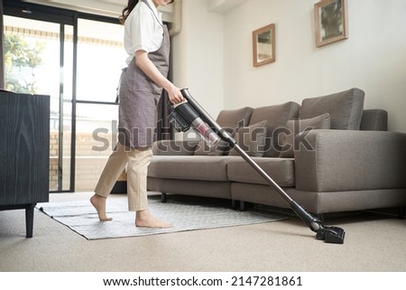 Asian woman vacuuming in the living room Royalty-Free Stock Photo #2147281861