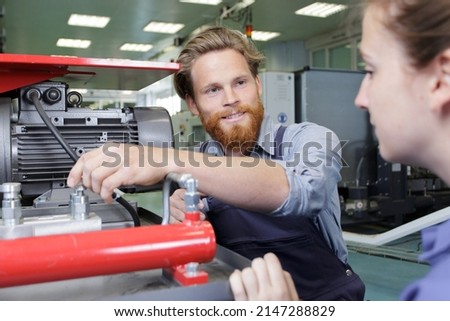 engineer showing machinery to female trainee Royalty-Free Stock Photo #2147288829