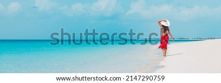 Beach vacation woman walking on summer travel Caribbean holiday wearing white sun hat and sarong skirt. Ocean panoramic banner background. Elegant lady tourist Royalty-Free Stock Photo #2147290759