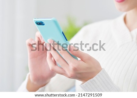Asian woman using the smartphone at home, no face