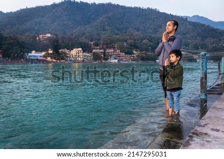 isolated young man and kid prying the holy ganges river at river bank from flat angle image is taken at ganga river bank rishikesh uttrakhand india. Royalty-Free Stock Photo #2147295031