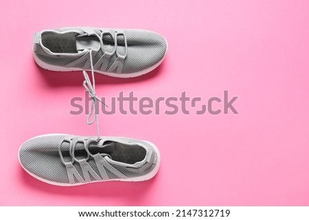 Shoes with tied laces on pink background. April Fool's Day prank