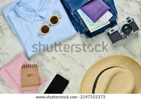 Frame made of passport with clothes, photo camera and mobile phone on grunge background