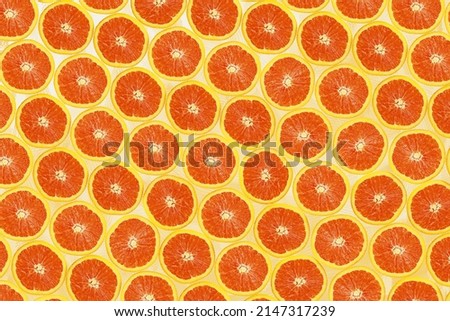 Top view of orange fruit half slices on orange pastel background for background or wallpaper.