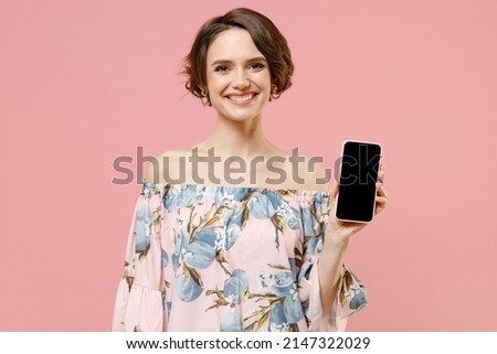 Young happy fashionable caucasian woman with short hairdo wear trendy stylish blouse hold mobile cell phone with blank screen workspace area isolated on pastel pink color background studio portrait.