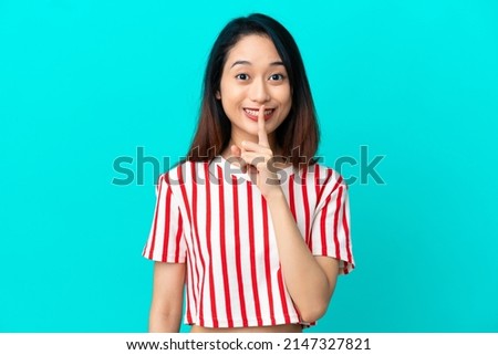 Young Vietnamese woman isolated on blue background showing a sign of silence gesture putting finger in mouth