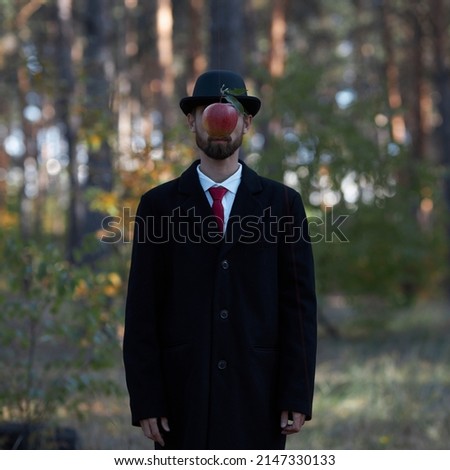Theme of surrealism: a man in a black coat, red tie and black bowler hat with a forest in the background. Orreal depiction of a man in a suit and bowler hat, based on a painting by Rene Magritte. Royalty-Free Stock Photo #2147330133