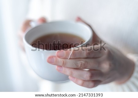 close up of woman's hands holding a big white cup of hot tea Royalty-Free Stock Photo #2147331393