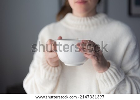 woman's hands holding a big white cup of hot tea Royalty-Free Stock Photo #2147331397