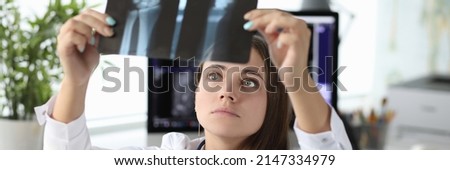 Woman doctor looking at xray of hand in clinic office