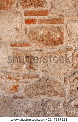 Old wall of large blocks and small bricks.
