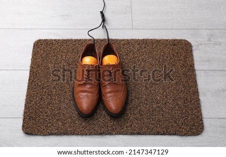 Shoes with electric dryer on rug indoors, above view