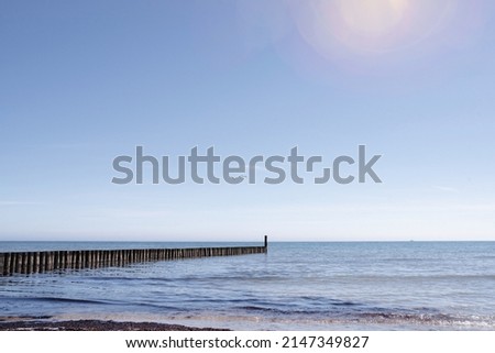beautiful seaside background, wooden breakwater in calm sea against clear blue sky