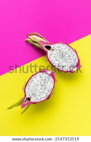 Dragon fruit, pitahaya: cut fruit on a colorful yellow and pink background, top view, copy space. Tropical fruits.