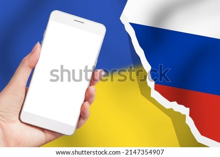 Information war Russia vs Ukraine. Ukrainian news channel. Female hand holds a mobile phone with a blank white screen and female hands hold a heart with a picture of the flag of Ukraine isolated over