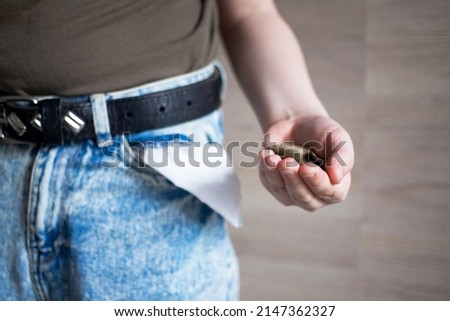 a handful of coins near the pocket of jeans pants as a sign or symbol of wealth or the last money from coins.