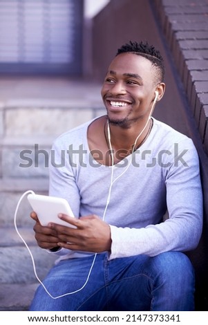 Im so downloading this whole album. Shot of a young man listening to music while sitting on a staircase outside.