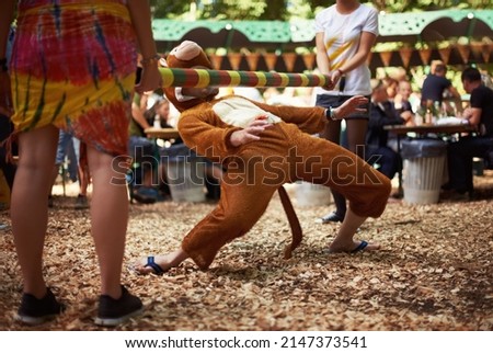 Monkeying around. A guy dressed in a monkey costume doing the limbo dance at a music festival. Royalty-Free Stock Photo #2147373541