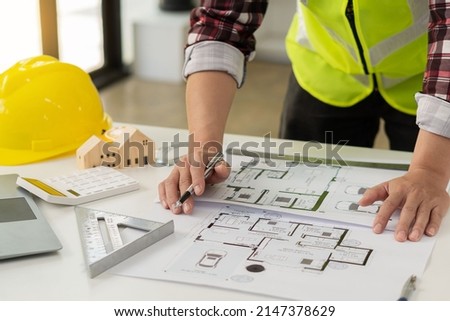 Professional architect working on blueprints and construction plans. Building engineers calculate and draft building construction drawings, civil engineering, and construction business concepts.
