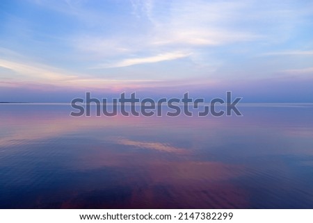 Sky background on sunset, colorful clouds. Nature abstract composition with reflections on sea water, natural blue pink purple shades of skyline. Nature environment. Royalty-Free Stock Photo #2147382299