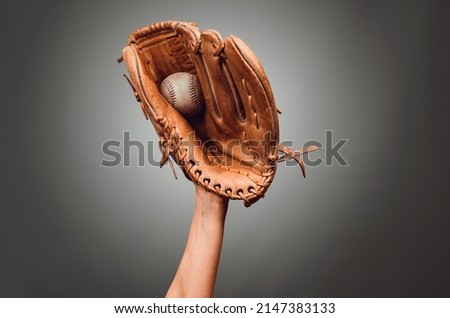 Hand in leather baseball glove caught a ball on dark gray background Royalty-Free Stock Photo #2147383133
