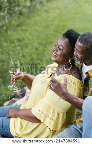 high angle view of smiling and senior african american couple holding glasses of wine