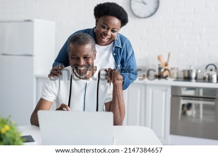 happy african american man and woman looking at laptop Royalty-Free Stock Photo #2147384657