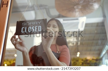 Owner coffee shop woman hand flip the sign to closed the shop.closed sign hanging on the glass door.